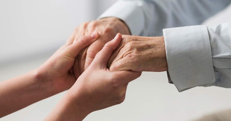 A nurse holding hands of an elderly patient